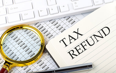 TAX REFUND text on the notebook with chart, magnifier,keyboard and pen