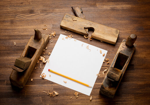 Blank business card on wooden table for carpenter tools with sawdust top view.