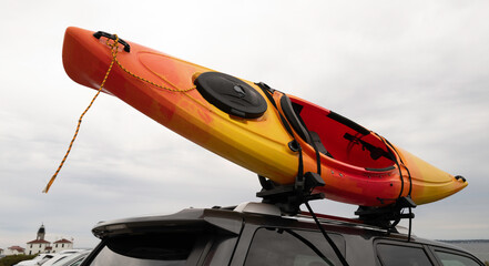 Red and orange colored kayak on the rooftop of a car