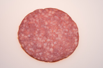 Fresh salami sausage slices on white surface

