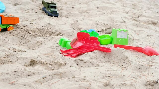Childrens plastic toys lying on the white sand. Concept for summer games and children occupation