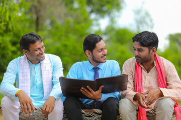 young india bank officer completing paper work with farmers at home.