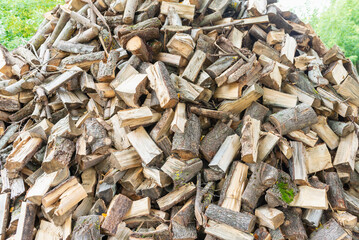 Fuel and heat source for the winter season.Preparing for the firewood heating season. Chopped firewood of different trees,outdoors.