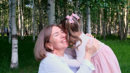 cute granddaughter, 3 years old, tells her happy smiling grandmother a secret in her ear. The concept of a happy relationship between generations, raising children