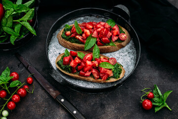 Bruschetta with pesto and tomatoes on a dark background