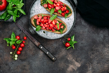 Bruschetta with pesto and tomatoes on a dark background