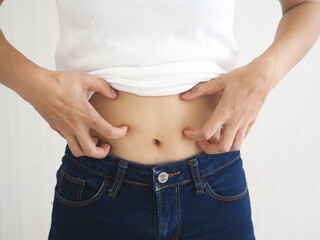 Fototapeta premium Asian woman scratching her stomach. caused by hives, insect bites, health care concepts. closeup photo, blurred.