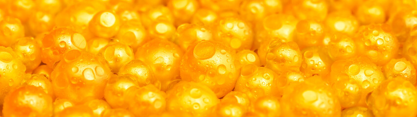 Beautiful background with pearl gold pearls, top view. Abstract texture for festive backgrounds. Shiny yellow surface of Christmas decorations. Gems close-up. Golden bright background.