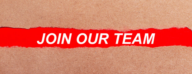 A strip of red paper under the torn brown paper. White lettering on red paper JOIN OUR TEAM. View from above