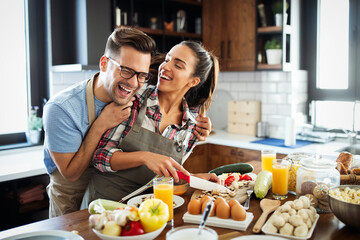Happy young couple have fun in modern kitchen while preparing fresh food