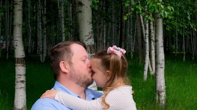 Dad gently kisses his little daughter, 3 years old, on the cheek. Fathers day. Happy childhood concept..