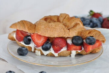 fresh croissant with cream, strawberries and blueberries