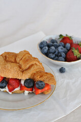 fresh croissant with cream, strawberries and blueberries
