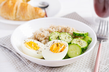 Breakfast oatmeal porridge with boiled egg, cucumber and sesame seed. Healthy balanced food.