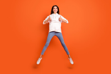 Fototapeta na wymiar Full length body size view of attractive lucky cheerful girl jumping showing thumbup isolated over bright orange color background
