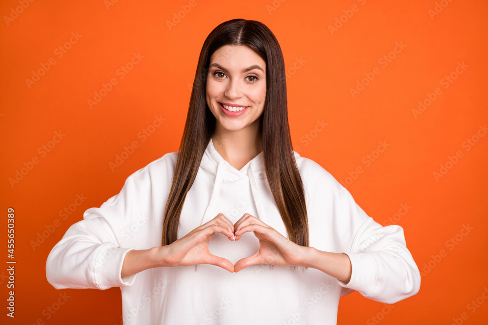 Canvas Prints Portrait of attractive amorous cheerful brunette girl showing heart symbol isolated over bright orange color background