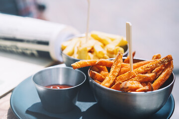 Fried sweet potatoes and French fries with mayonnaise and ketchup in beer pub. Popular street junk food or snack for beer or side dish in restaurant.