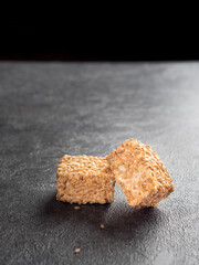 Traditional milky sweet oriental dessert Turkish delight (rahat locum) with sesame seeds on a gray background. Side view. Copy space.