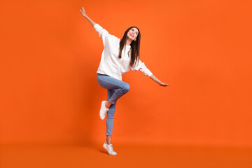 Fototapeta na wymiar Full length body size view of attractive cheerful carefreee girl dancing flying fooling isolated over bright orange color background