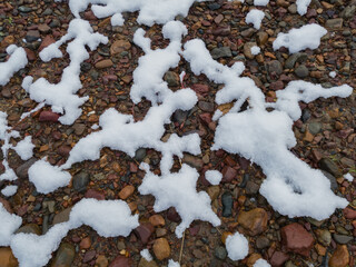 Snow pattern on wet gravel terrain, snow melting