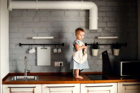 Cute toddler girl child in a dress in a stylish kitchen children's safety in apartments, a cozy photo in a scandinavian interior