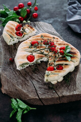 Focaccia with tomatoes and herbs on a wooden table
