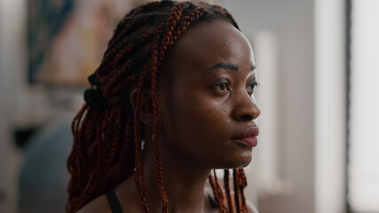 Close-up of african woman meditating in lotus position sitting on yoga mat with closed eyes at home...