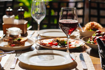 wooden table served with plates with salad and snacks on the open terrace