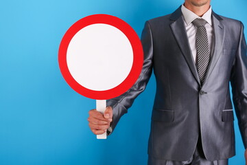  businessman holding a round sign with mockup on a blue background close-up. a person wearing a suit holds a sign with mockup