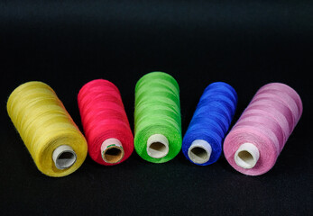 colorful spools of thread on black background