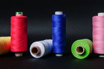 colorful spools of thread on black background