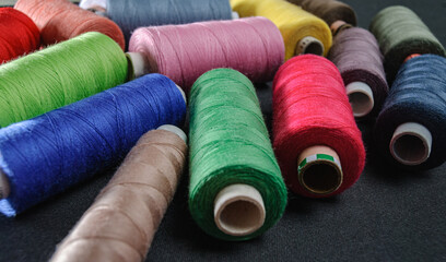 colorful spools of thread on black background
