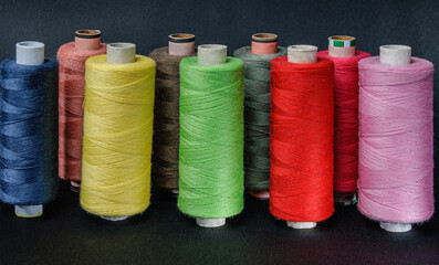colorful spools of thread on black background