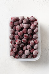 Frozen red sour cherry in container on white background. View from above. Vertical format.