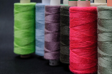 colorful spools of thread on black background