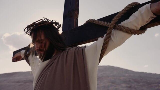 Jesus crucified on the cross, the wind is blowing, the sun is shining. Crucifixion. On the head is a wreath of thorns. Crown of thorns. High quality 4k footage