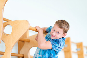 Kid at physical education lesson in school gym. Boy in gym doing pull ups. Horizontal education poster, greeting cards, headers, website. Safe back to school during pandemic concept