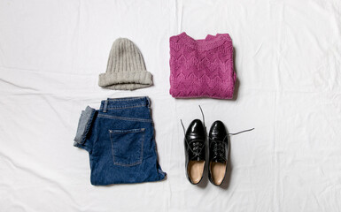 knitted sweater, jeans and shoes on a white background. Top view of a casual women's casual outfit. Flat lay, top view. Women's clothing.