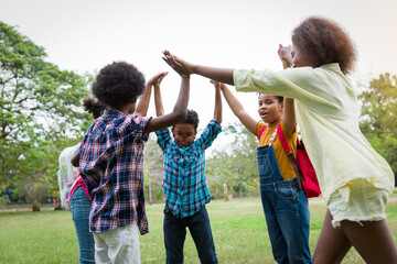 Group of African American children joining their hands in the park. Diverse black children joining their hands. Successful and teamwork concept