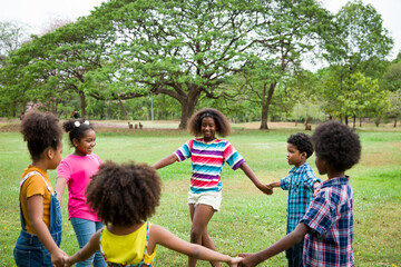 Group of African American children joining their hands in the park. Diverse black children joining their hands. Successful and teamwork concept