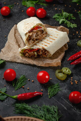Delicious shawarma and lavash tacos on a dark stone table. Fast food restaurant. Healthy option of fast food. Tasty fresh wrap sandwiches with beef meat and vegetables, Traditional Middle Eastern snac