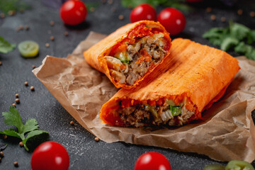 Delicious shawarma and tacos in a cheese lavash on a dark stone table. Fast food restaurant. Healthy option of fast food. Tasty fresh wrap sandwiches with beef meat and vegetables, Traditional Middle