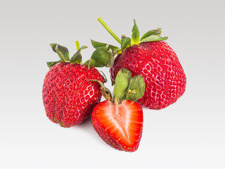 Cut in half and two whole strawberries on a light background