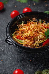 Delicious salad with tomatoes, roasted potatoes, tomatoes and fresh herbs, a fresh salad on the menu of a fast food restaurant on a dark stone table. Healthy option of fast food..