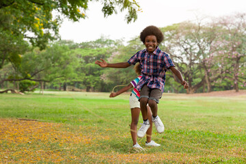 Group of African American children having fun jumping over the rope in the park. Cheerful kid jumping over the rope outdoor. Happy black people enjoying playing together on green grass