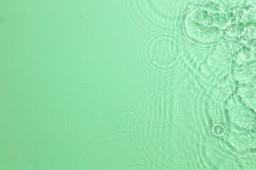 Green transparent clear water surface texture with ripples, splashes and bubbles. Abstract summer nature background. Top view image