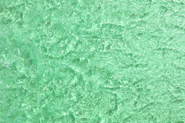 Transparent green water surface with ripples and splashes. Summer water background in sunlight. copy space. Copy space Cosmetic, toner, mask, moisturizer.