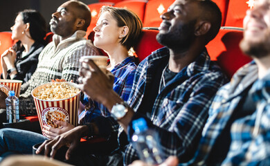 Friends watching a movie in the cinema with popcorn. People sit in the armchairs of the cinema and look at the screen