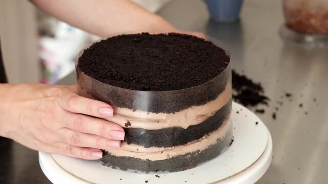 4K Woman pastry chef makes chocolate cake in an acetate film, close-up. Slow motion. Cake making process