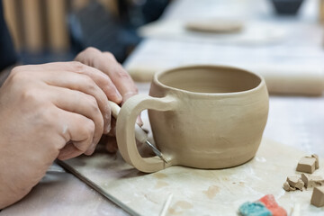 Fototapeta na wymiar a ceramic artist processes the handle of a clay mug